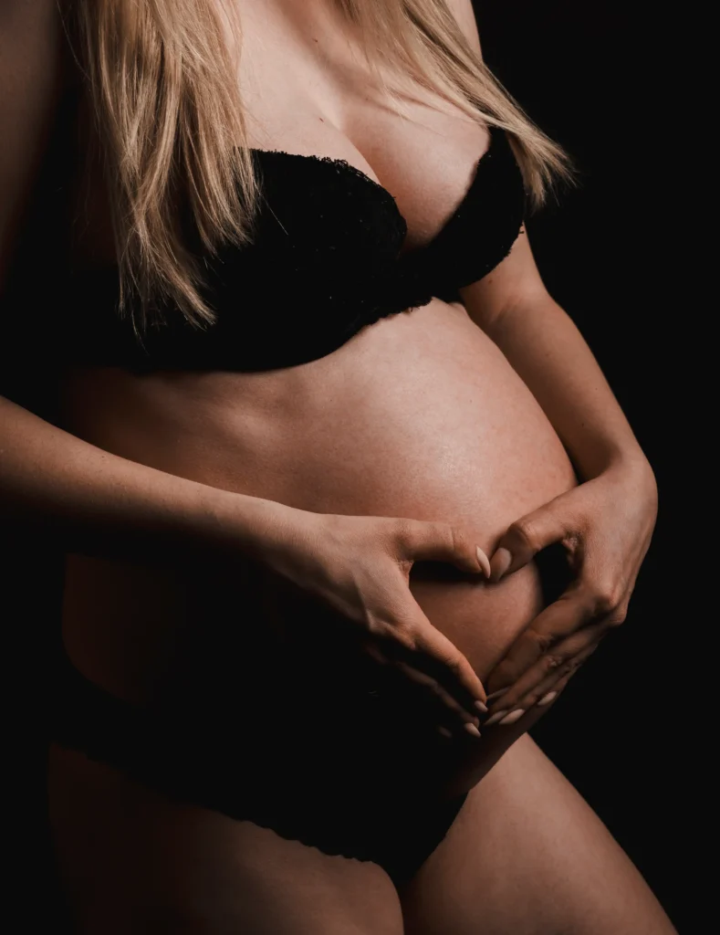 Schwangere Frau mit schwarzen Dessous mit Händen auf dem Bauch – Babybauchshooting Koblenz